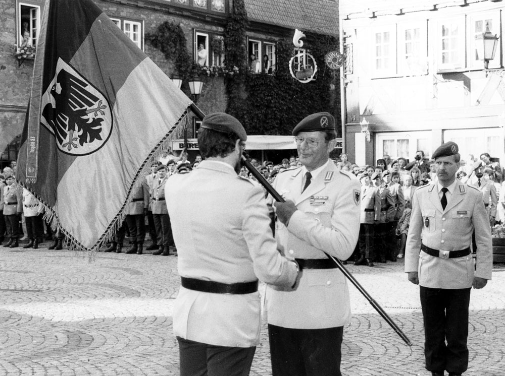 OTL Richter gibt die Truppenfahne des NschBtlSw 320 an den KArtKdr 3 Oberst Eckermann zurück